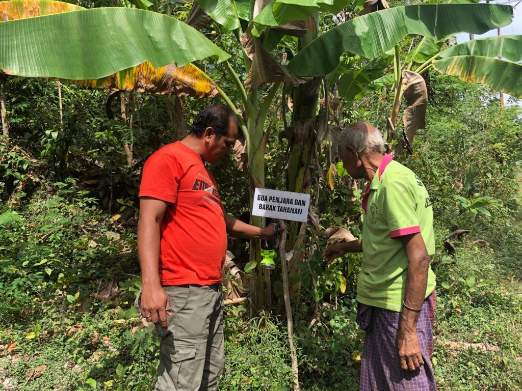 Pendeta Oetniel Dhany Liu bersama seorang warga Kampung Bonen, Desa Baumata, Kabupaten Kupang memperbaiki plang nama satu gua pada Juni 2022. (Ruth- KatongNTT.com)