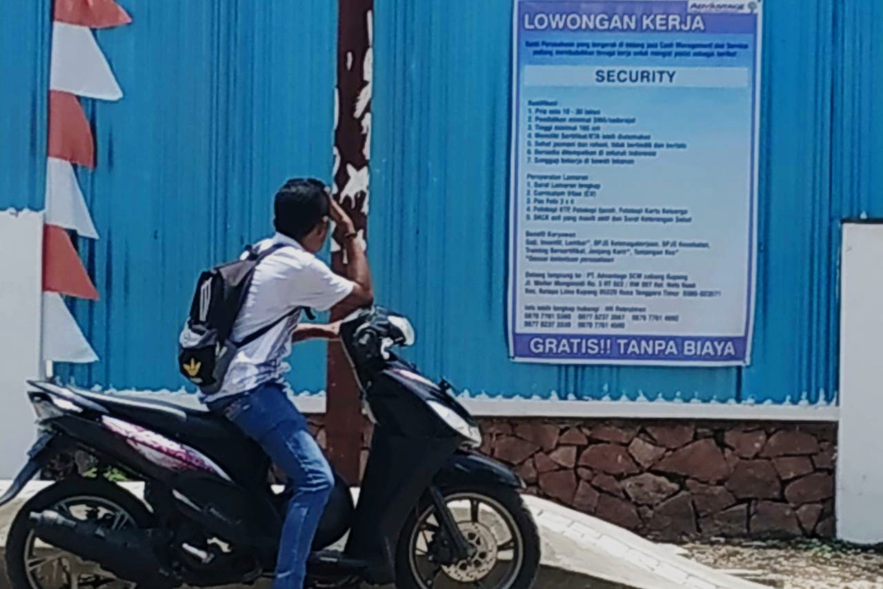 Seorang pencari kerja membaca papan lowongan kerja di sekitar wilayah Nefonaek Kota Kupang beberapa waktu lalu. (Putra Bali Mula - KatongNTT,com)