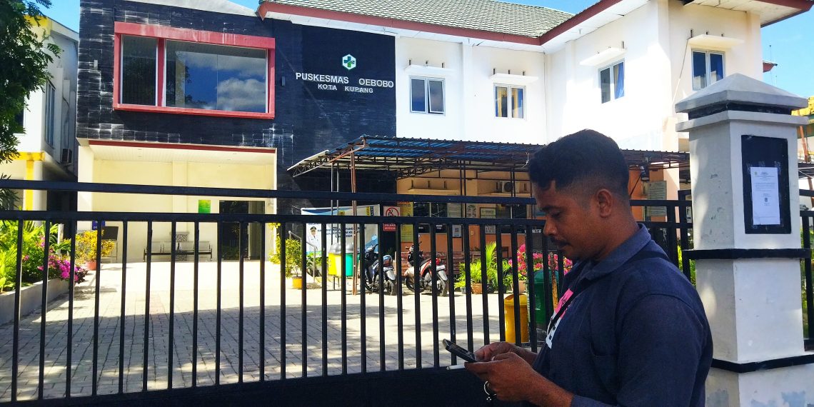 Salah seorang warga di depan pagar Puskemas Oebobo yang terkunci. (Putra Bali Mula - KatongNTT).