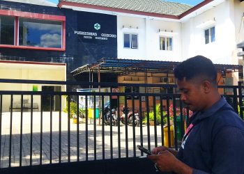 Salah seorang warga di depan pagar Puskemas Oebobo yang terkunci. (Putra Bali Mula - KatongNTT).