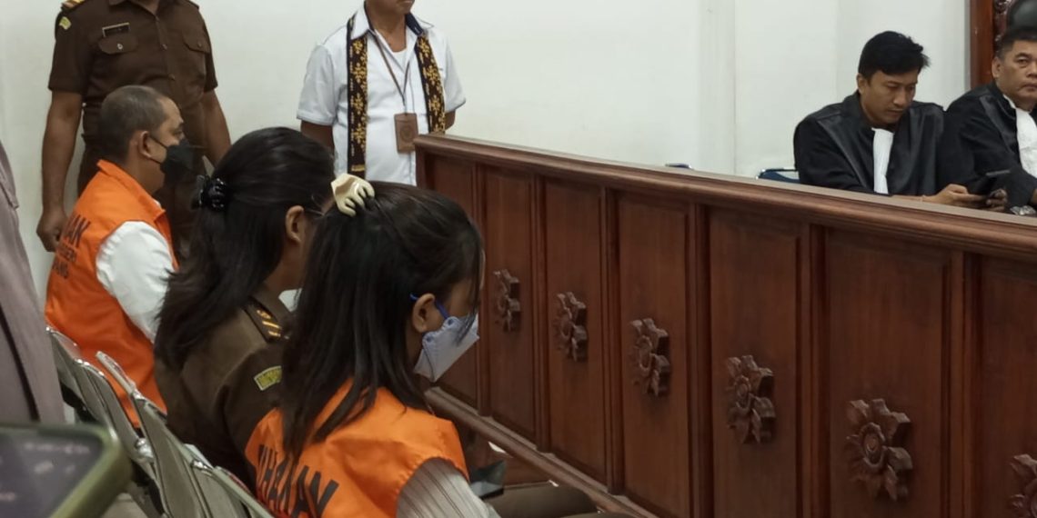 Sidang perdana eks Kapolres Ngada, NTT Fajar Widyadarma Lukman Sumaatmaja , terdakwa pencabulan tiga anak dan menyebarkan video cabulnya di situs porno di Australia (paling kiri duduk mengenakan baju oranye) dan terdakwa Stefani Heidi Doko Rehi (paling kanan duduk pakai baju oranye), yang membawa tiga anak kepada Fajar. Kedua terdakwa diadili di PN Kupang pada 30 Juni 2025. (Novita/KatongNTT)