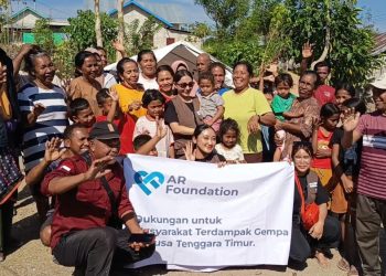 Julia Purmawati, pendiri AR Foundation (berdiri mengenakan kacamata menggendong anak) menyerahkan bantuan kemanusiaan kepada warga Desa Satar Padut, Kecamatan Lamba Leda Utara, Manggarai Timur pada Jumat, 29 Agustus 2026. (Dok. KatongNTT)