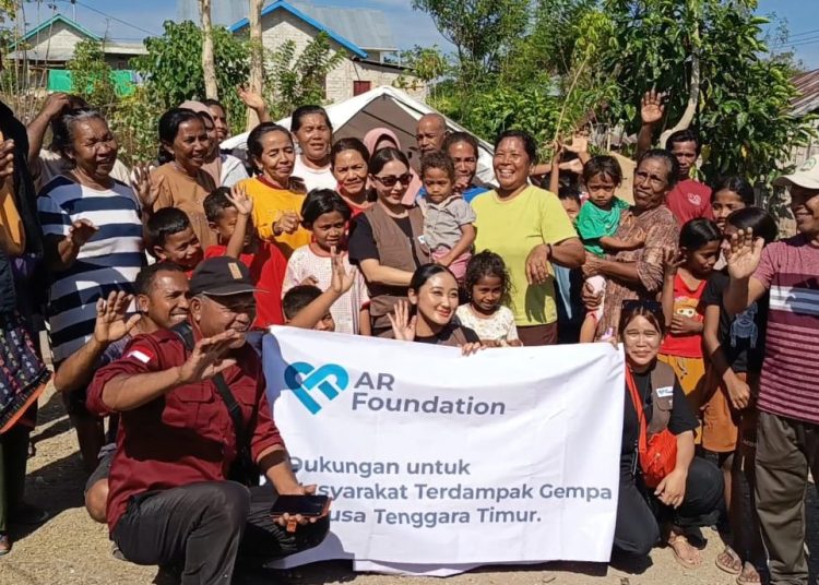 Julia Purmawati, pendiri AR Foundation (berdiri mengenakan kacamata menggendong anak) menyerahkan bantuan kemanusiaan kepada warga Desa Satar Padut, Kecamatan Lamba Leda Utara, Manggarai Timur pada Jumat, 29 Agustus 2026. (Dok. KatongNTT)